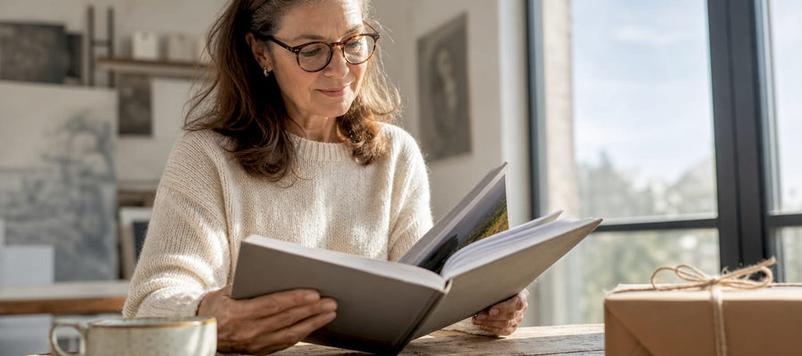 Eine Frau blättert entspannt zu Hause durch ihr individuell gestaltetes Fotobuch und erinnert sich an besondere Momente.