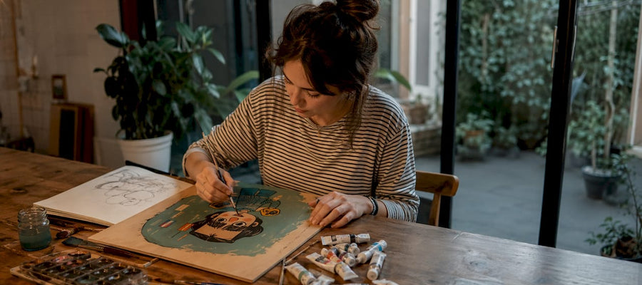 Ein Künstler sitzt in einem lichtdurchfluteten Atelier und zeichnet Karikaturen.